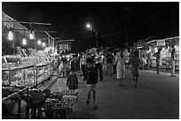 Shoppers walk past craft booth at night market. Phu Quoc Island, Vietnam ( black and white)