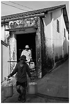 Workers carrying out containers of nuoc mam, Duong Dong. Phu Quoc Island, Vietnam (black and white)