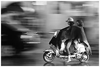 Women riding scooter in the rain. Ho Chi Minh City, Vietnam (black and white)