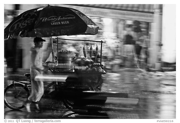 Man riding riding food cart in the rain. Ho Chi Minh City, Vietnam (black and white)