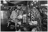 Women riding motorbikes buy sweet rice. Ho Chi Minh City, Vietnam (black and white)