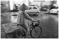 Woman rides bicycle in the rain. Ho Chi Minh City, Vietnam ( black and white)