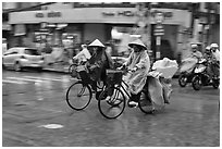 Women riding bicyles in the rain. Ho Chi Minh City, Vietnam (black and white)