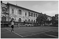 Men play tennis in front of colonial-area courthouse. Ho Chi Minh City, Vietnam (black and white)