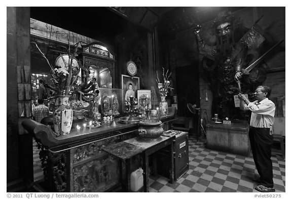 Man in prayer, with fierce statue of general behind, Jade Emperor Pagoda, district 3. Ho Chi Minh City, Vietnam