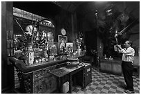 Man in prayer, with fierce statue of general behind, Jade Emperor Pagoda, district 3. Ho Chi Minh City, Vietnam (black and white)