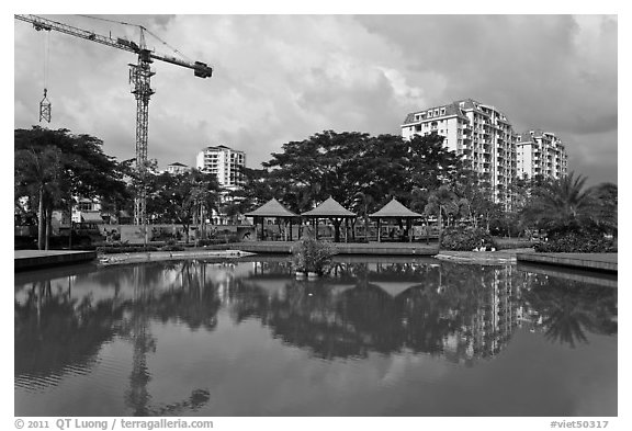 Reflecting pool, completed residential buildings, and crane, Phu My Hung, district 7. Ho Chi Minh City, Vietnam (black and white)