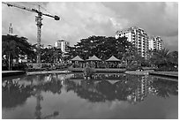 Reflecting pool, completed residential buildings, and crane, Phu My Hung, district 7. Ho Chi Minh City, Vietnam (black and white)