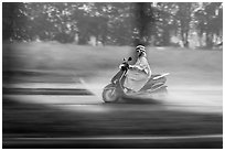 Scooter rider in the rain on parkway, district 7. Ho Chi Minh City, Vietnam (black and white)