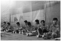 Uniformed students sitting in front of backdrops depicting traditional landscapes. Ho Chi Minh City, Vietnam (black and white)