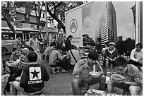 Uniformed students eating breakfast in front of backdrop depicting high rise in construction. Ho Chi Minh City, Vietnam (black and white)