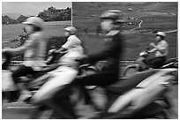 Motorbike riders speeding in front of backdrops depicting traditional landscapes. Ho Chi Minh City, Vietnam (black and white)