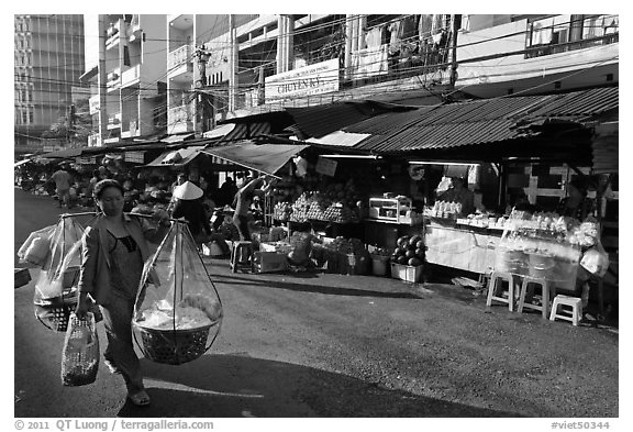 Woman carrying goods on street market. Ho Chi Minh City, Vietnam (black and white)