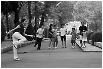 Young woman playing footbag as audience watches, Cong Vien Van Hoa Park. Ho Chi Minh City, Vietnam ( black and white)