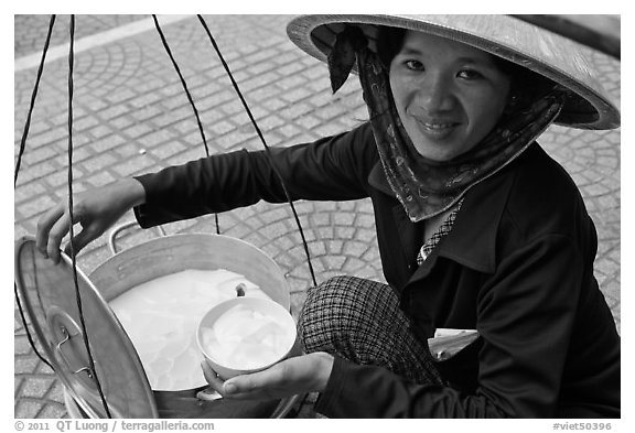 Woman smiling while handling bowl of soft tofu. Ho Chi Minh City, Vietnam (black and white)