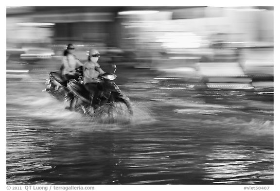 Motorcycle riders, water splashes, and streaks of light. Ho Chi Minh City, Vietnam