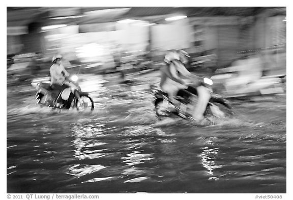 Motion-blured exposure of riders on flooded street at night. Ho Chi Minh City, Vietnam