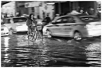 Women riding a bicycle on a flooded street at night. Ho Chi Minh City, Vietnam (black and white)