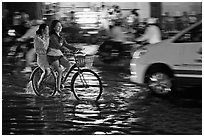 Women sharing a bicycle ride at night on a water-filled street. Ho Chi Minh City, Vietnam (black and white)