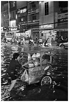 Vendor pushing foot car into the water at night. Ho Chi Minh City, Vietnam ( black and white)
