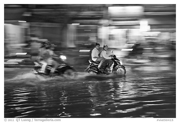Motorcycles riding through the water on street with motion. Ho Chi Minh City, Vietnam (black and white)