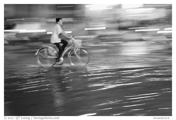 Night Bicyclist, water, and motion light streaks. Ho Chi Minh City, Vietnam