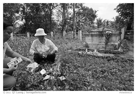 Women burning fake money as offering. Ben Tre, Vietnam (black and white)