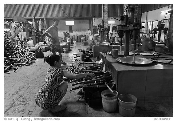 Woman feeding furnace in cococut candy factory. Ben Tre, Vietnam (black and white)