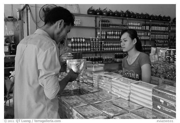Customer buying box of coconut candy. Ben Tre, Vietnam (black and white)