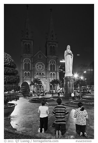 Family in prayer outside Notre-Dame Basilica at night. Ho Chi Minh City, Vietnam (black and white)