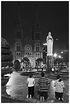 Family in prayer outside Notre-Dame Basilica at night. Ho Chi Minh City, Vietnam (black and white)