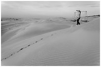 Woman descending sandhill with pannier baskets. Mui Ne, Vietnam (black and white)