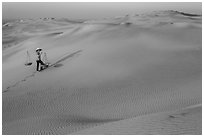 Red sand dunes and woman with carrying pole and baskets. Mui Ne, Vietnam (black and white)