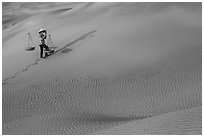 Woman walking with baskets on sands. Mui Ne, Vietnam (black and white)