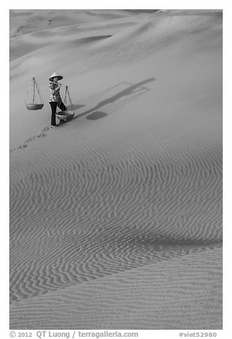 Woman with yoke baskets on sands. Mui Ne, Vietnam (black and white)