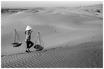 Woman carrying two baskets on shoulder pole. Mui Ne, Vietnam ( black and white)