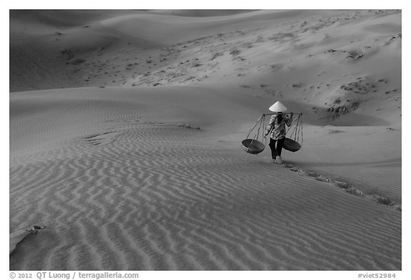 Woman with conical hat carries pannier baskets. Mui Ne, Vietnam