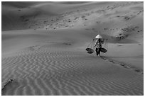 Woman with conical hat carries pannier baskets. Mui Ne, Vietnam ( black and white)