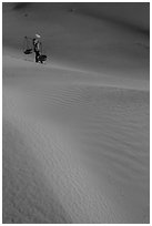 Woman with conical hat and shoulder pole baskets pauses on dune. Mui Ne, Vietnam ( black and white)