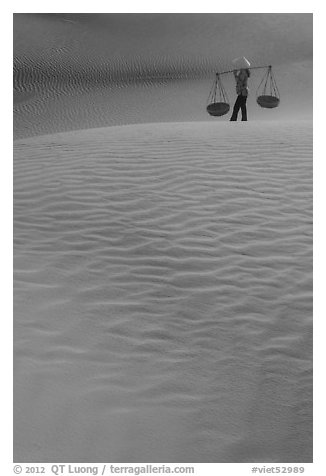 Figure with conical hats and two baskets on sand dunes. Mui Ne, Vietnam