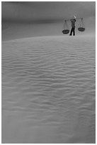 Figure with conical hats and two baskets on sand dunes. Mui Ne, Vietnam (black and white)