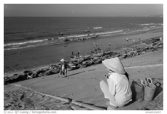 Woman on stairs overlooking beach with fishing boats. Mui Ne, Vietnam (black and white)