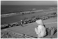 Woman on stairs overlooking beach with fishing boats. Mui Ne, Vietnam (black and white)