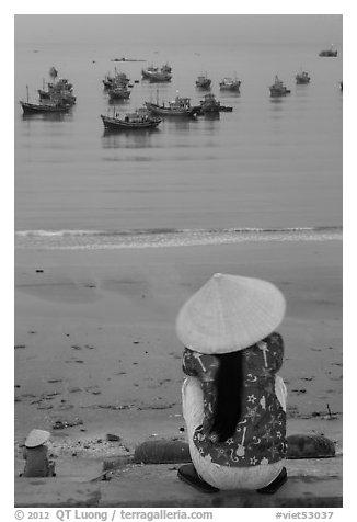 Woman with conical hat sitting above fishing fleet. Mui Ne, Vietnam