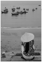 Woman with conical hat sitting above fishing fleet. Mui Ne, Vietnam (black and white)