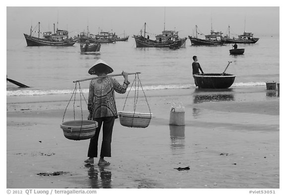 Woman with yoke baskets on beach. Mui Ne, Vietnam (black and white)
