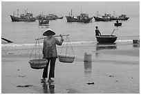 Woman with yoke baskets on beach. Mui Ne, Vietnam (black and white)