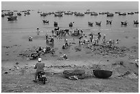 Man on motorbike looks over beach and harbor. Mui Ne, Vietnam (black and white)