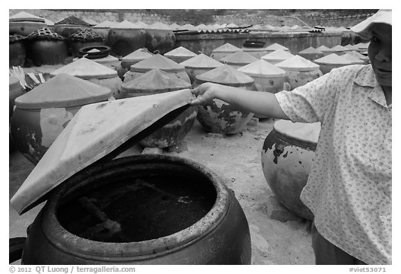 Woman examining vat of fish sauch. Mui Ne, Vietnam (black and white)