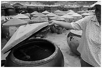 Woman examining vat of fish sauch. Mui Ne, Vietnam (black and white)